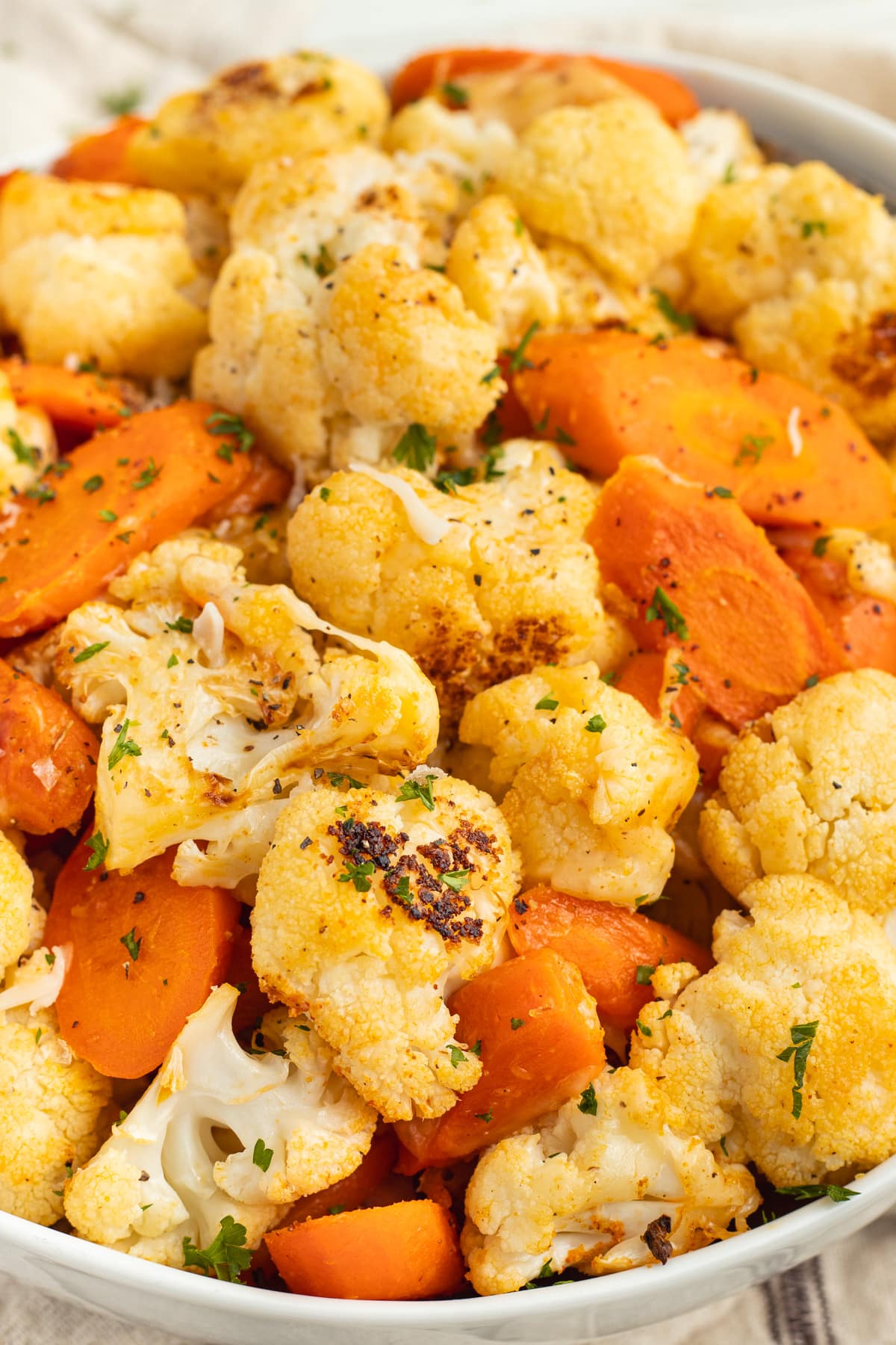 This is a picture of a bowl filled with cheesy carrots and cauliflower.