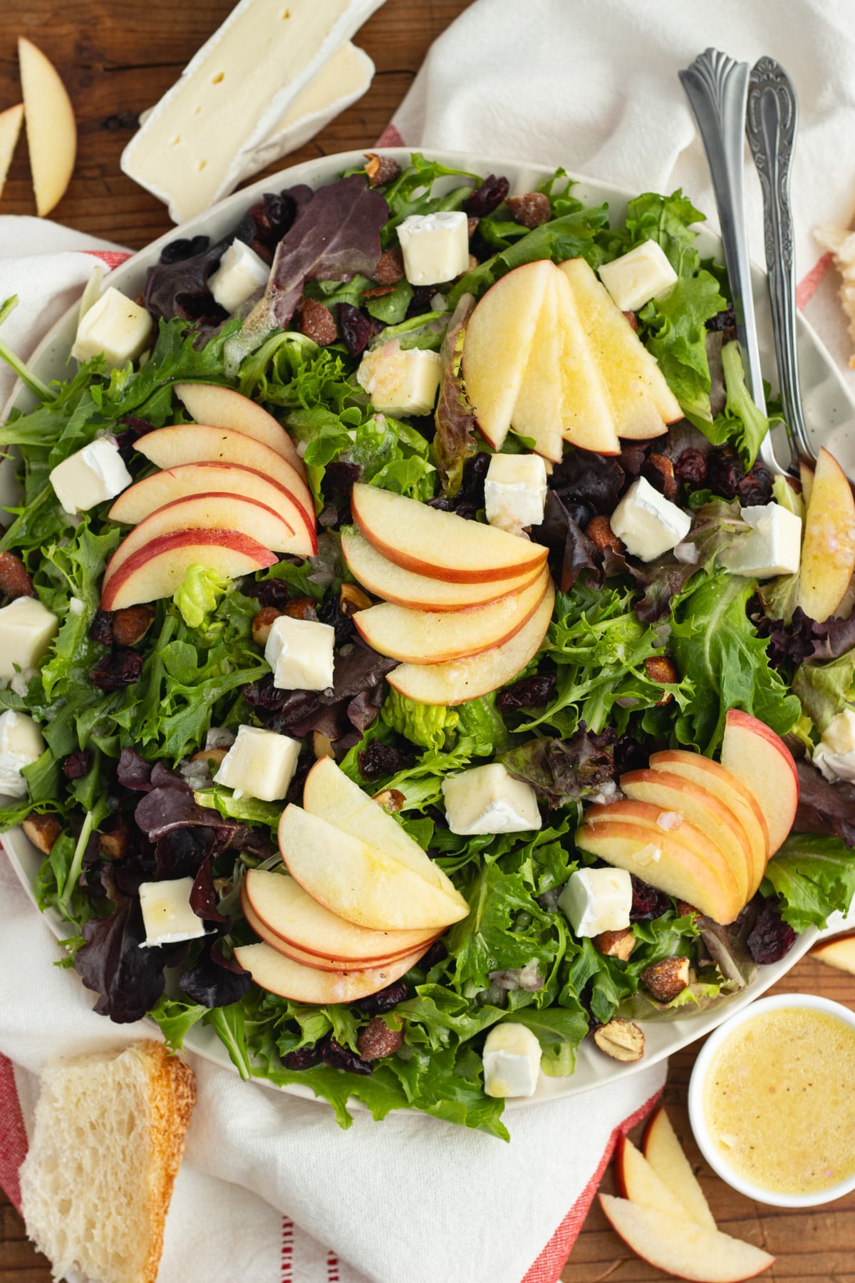 This is a picture of a plate filled with the salad with brie, apple, cranberries and almonds.