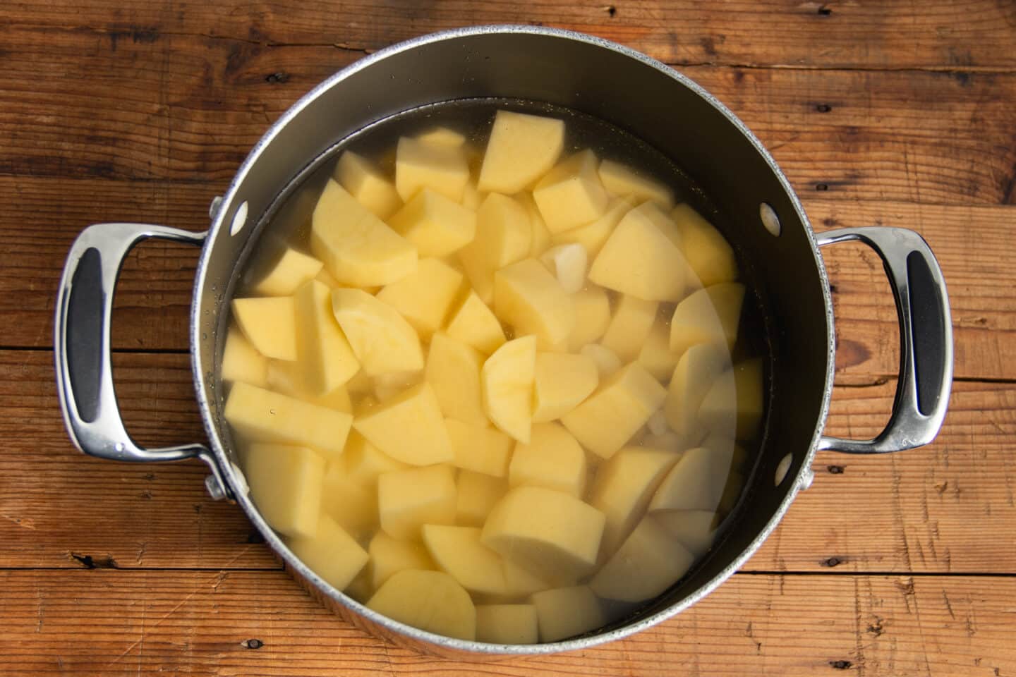 This is a picture of a pot with water and chopped potatoes.