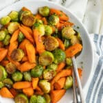 This is a square picture of a plate filled with roasted Brussels sprouts and carrots with hot honey.