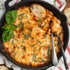 This is a square picture of cheesy white bean casserole in a skillet.