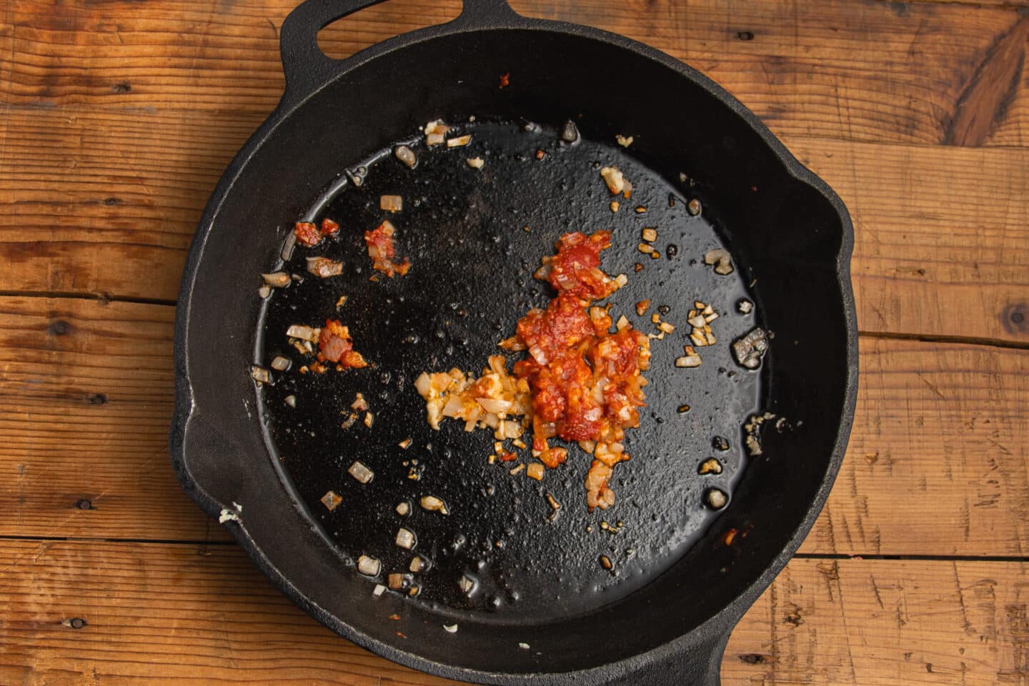 This is a picture of a skillet with added garlic and tomato paste.