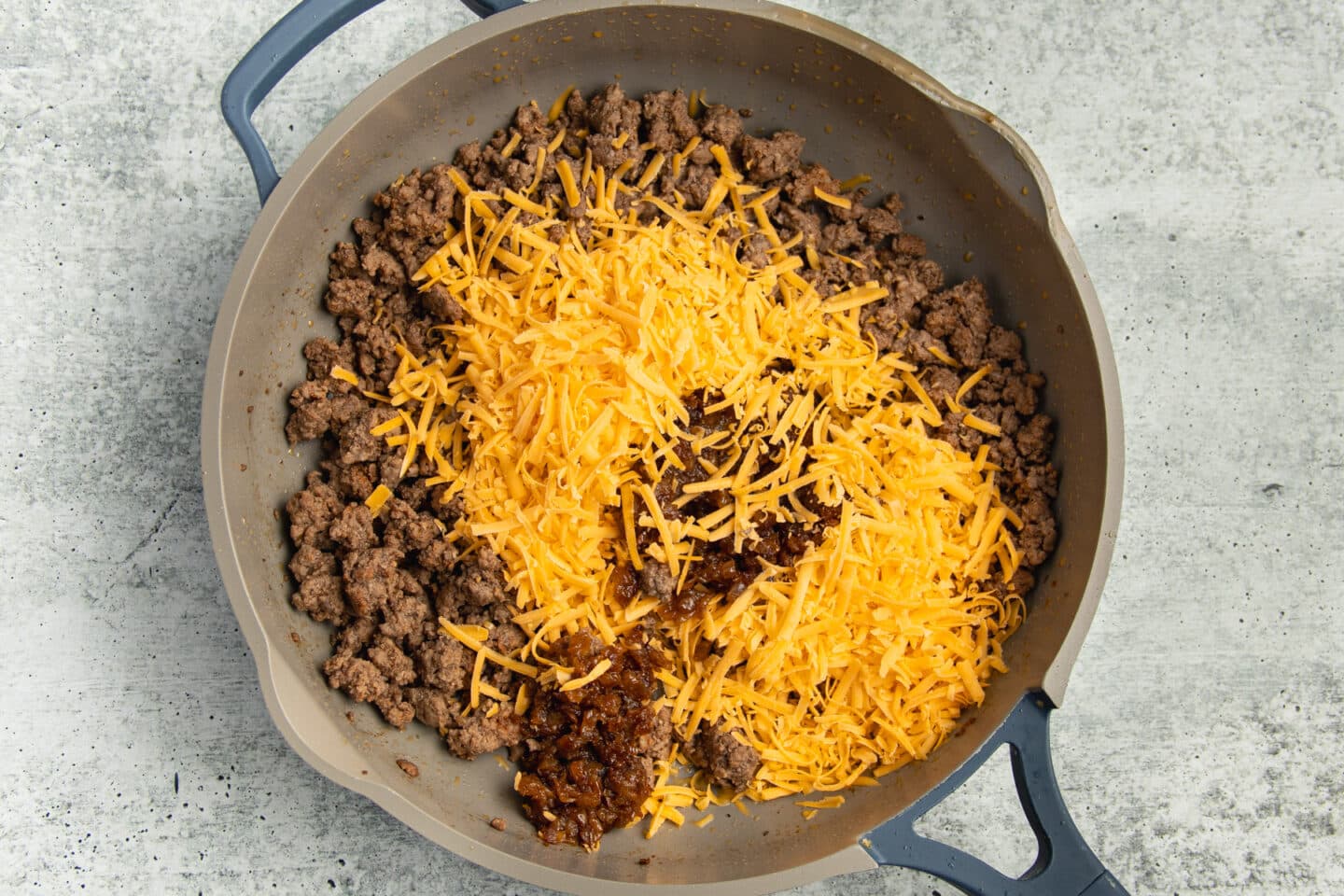 This is a picture of the skillet with ground beef, cheese and onions.