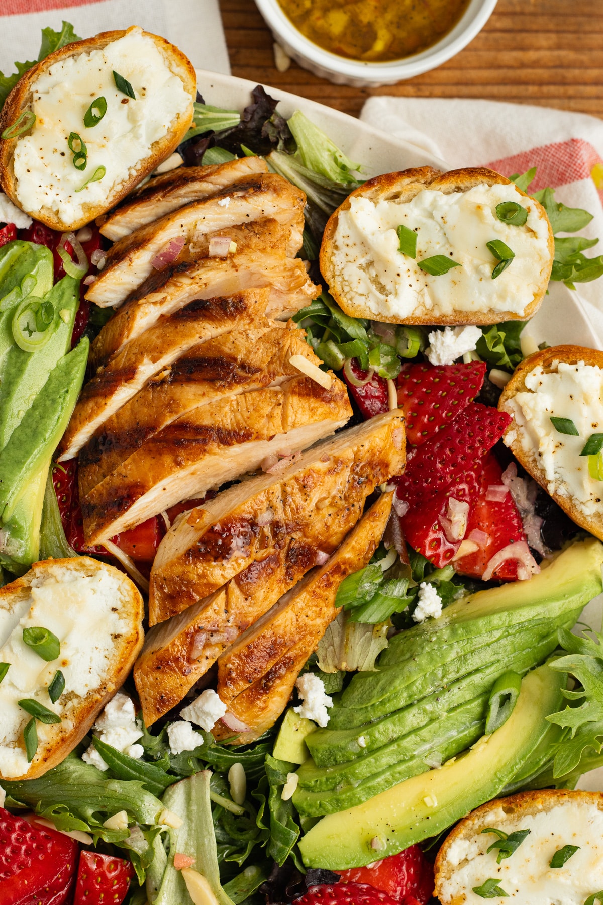 This is a picture of the grilled chicken salad with goat cheese crostini, avocado and strawberries.