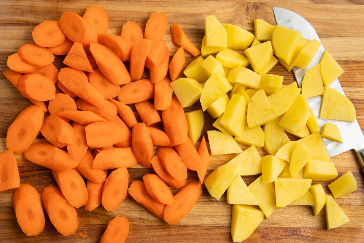 This is a picture of carrots and potatoes chopped on a cutting board.