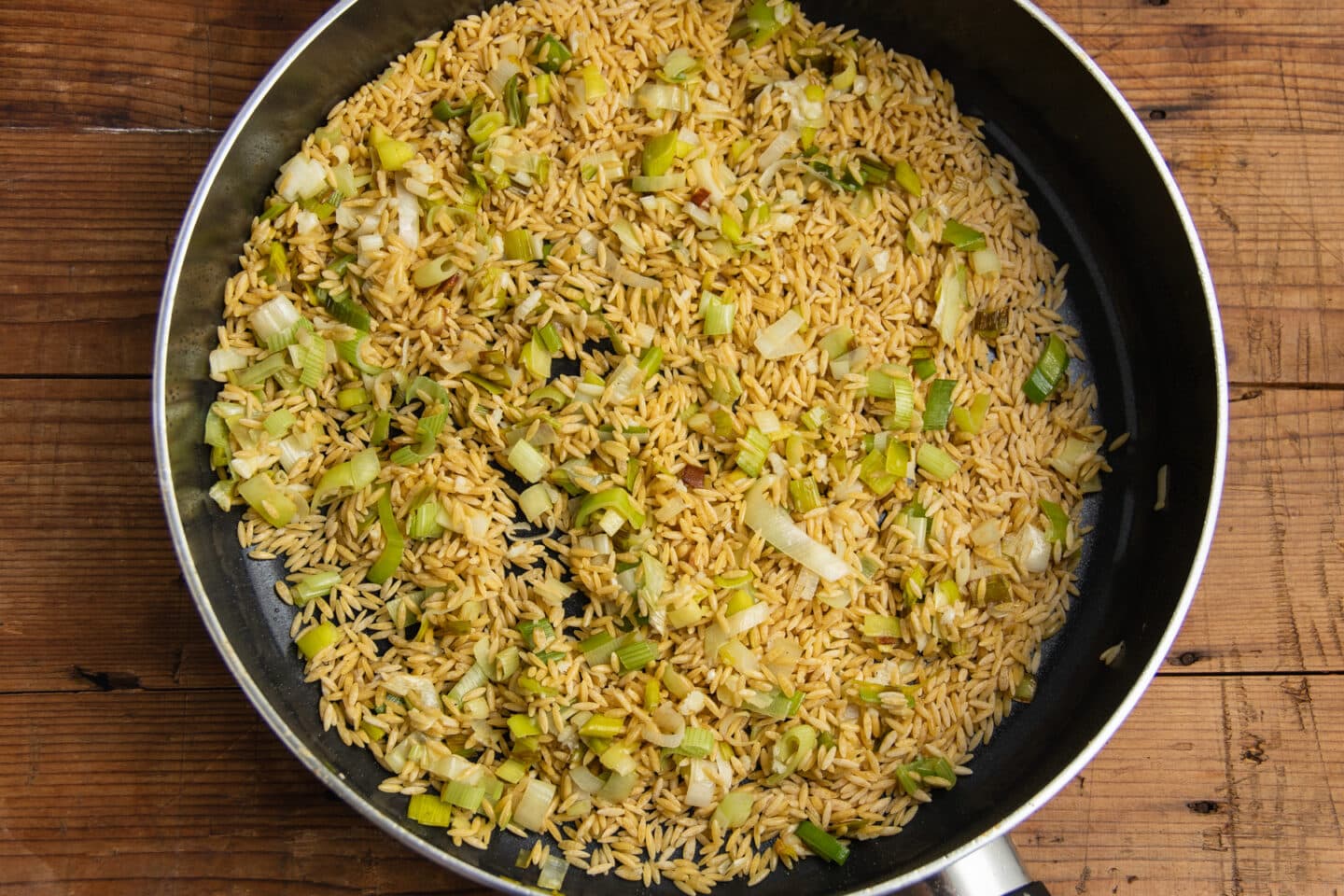 This is a picture of the skillet with the orzo added to the cooked leeks and garlic.