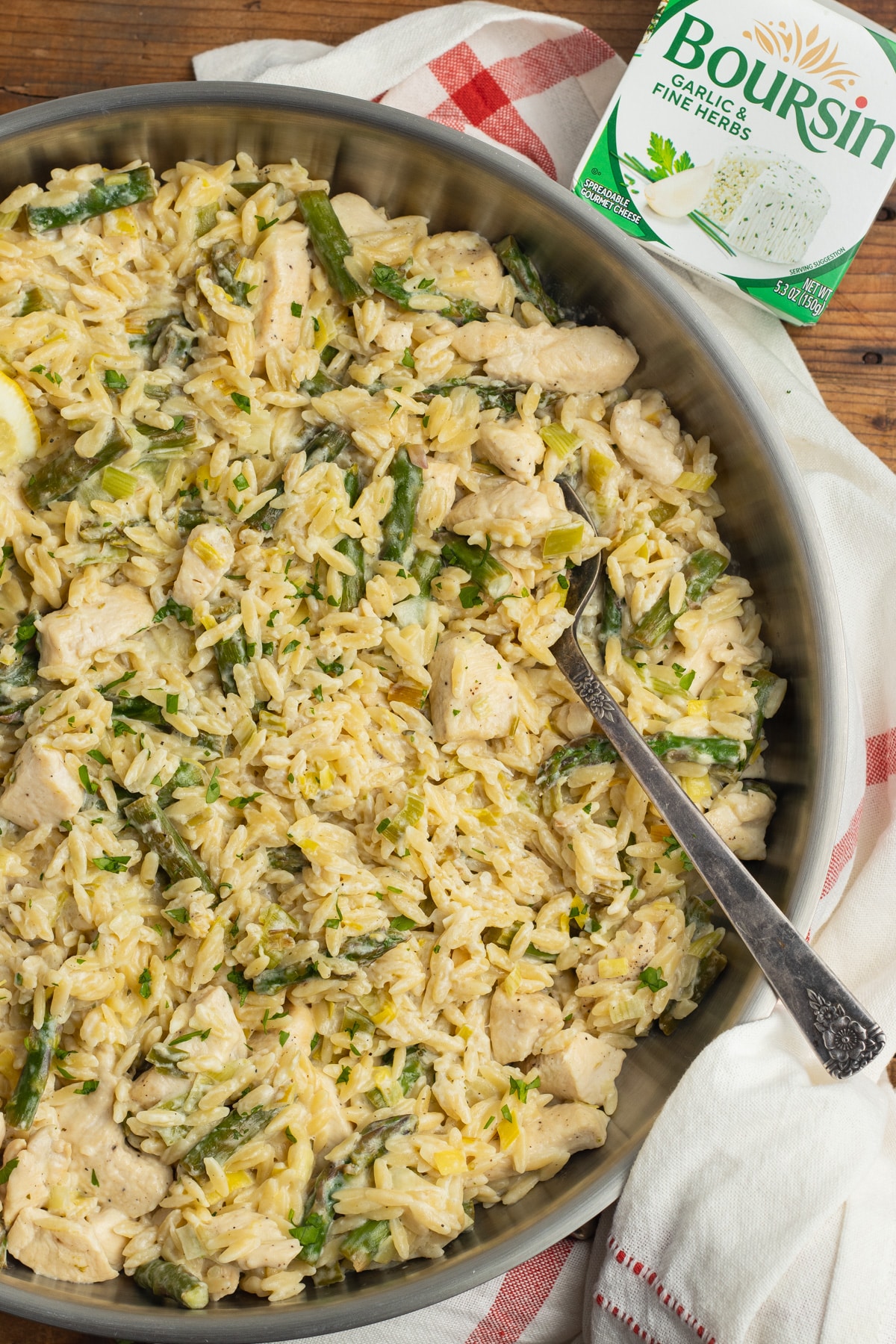 This is a picture of the chicken boursin orzo in a skillet with a package of boursin on the side.
