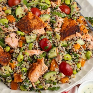 This is a square picture of salmon quinoa salad on a plate.