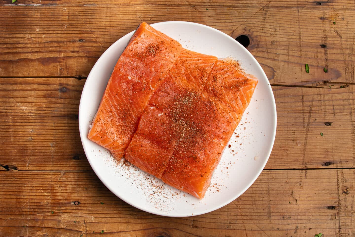 This is a picture of salmon filets with seasoning on a plate.