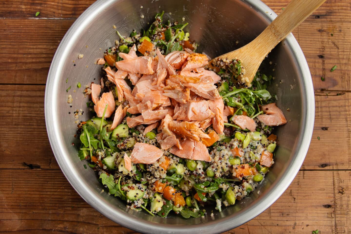 This is the quinoa salad being tossed in a bowl with the salmon and dressing.