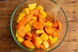 This is a picture of a bowl filled with chopped carrots and potatoes seasoned with herbs.
