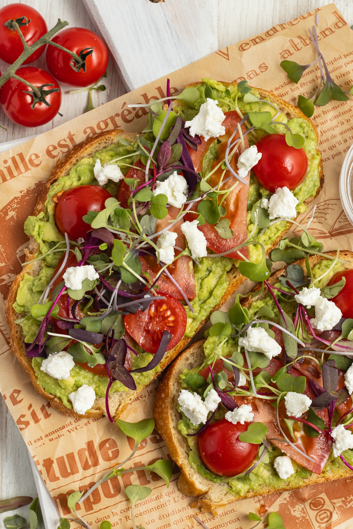 This is a picture of avocado toasts with tomato, goat cheese and microgreens.