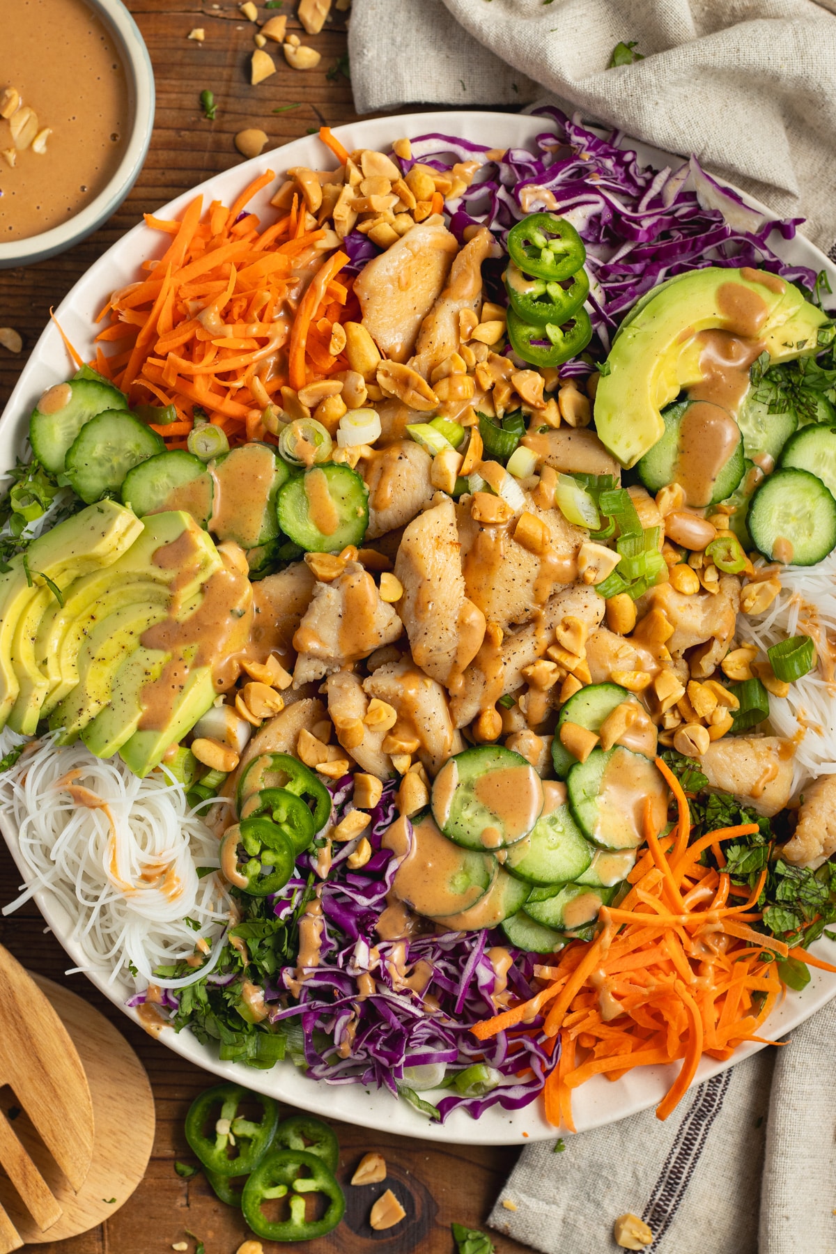 This is a picture of a large plate filled with chicken spring roll salad with peanut dressing.