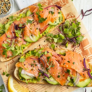 This is a square picture of two avocado toasts with smoked salmon.