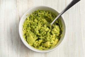 This is a bowl with smashed avocado.