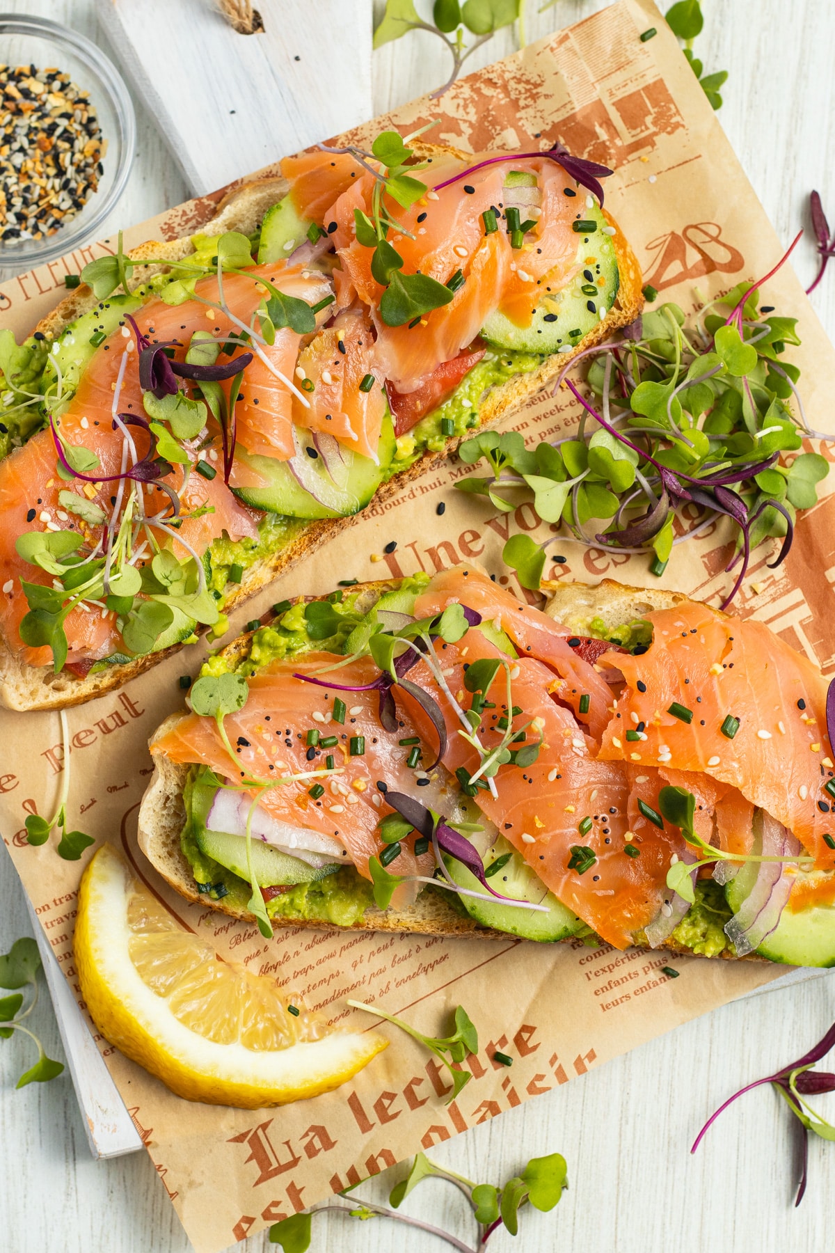 This is a picture of two avocado toasts with smoked salmon ready to serve.