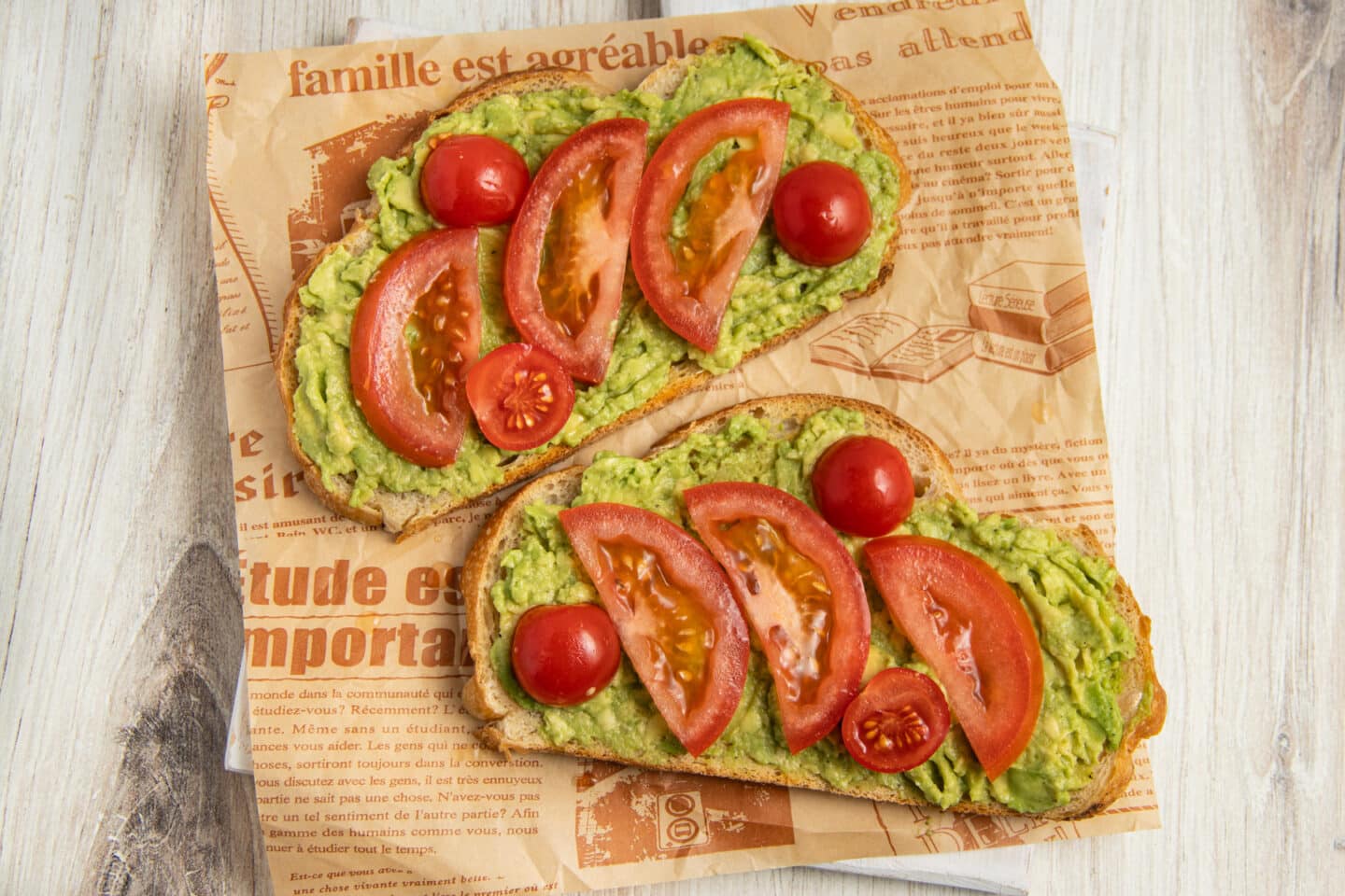 This is a picture of 2 toasts with smashed avocado and tomatoes added.