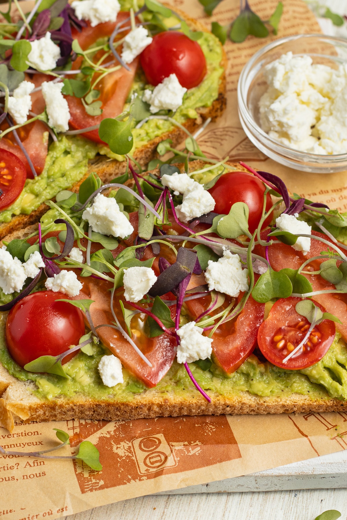 This is a picture of avocado toasts with tomato and goat cheese.