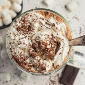 This is a square picture of bone broth hot chocolate with whipped cream and shaved chocolate.