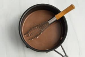 This is a picture of a sauce pan and a whisk with the hot chocolate.