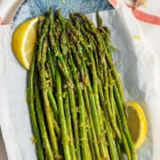 This is a square picture of a plate filled with lemon garlic asparagus.