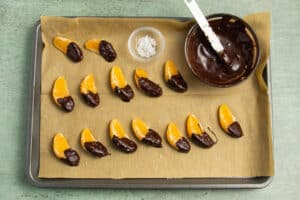 This is a picture of the oranges dipped and resting on parchment paper.
