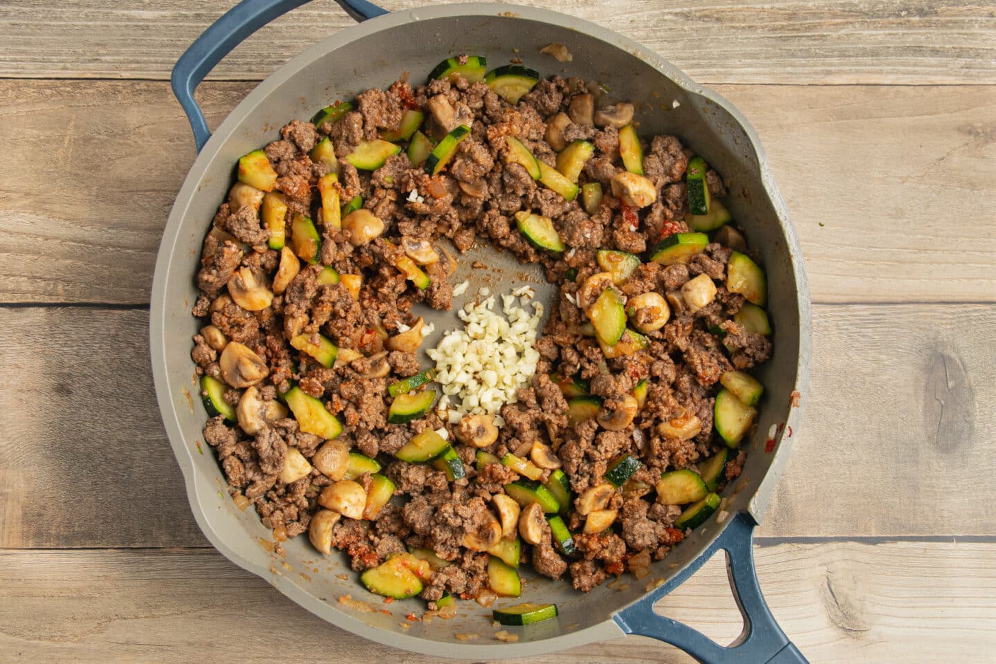 This is a picture of ground beef & veggies with added garlic cooking in a skillet.