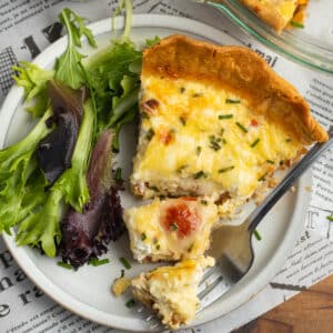 This is a square picture of tomato bacon goat cheese quiche with gruyere.