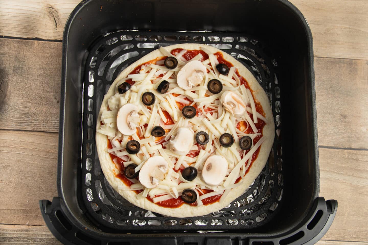 This is a picture of a tortilla pizza in the air fryer before cooking.
