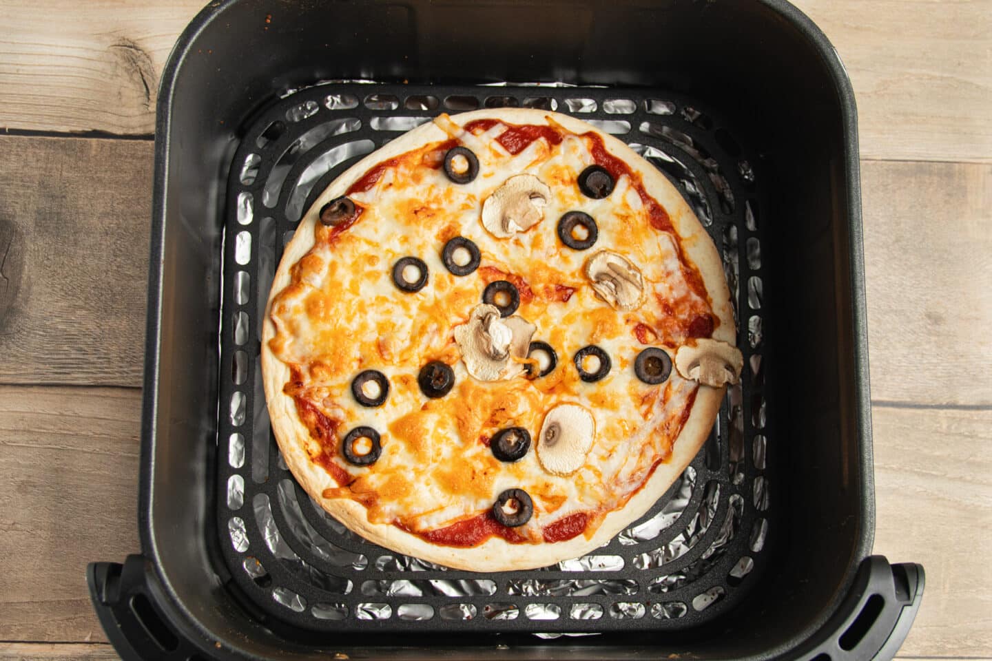 This is a picture of a tortilla pizza in the air fryer after cooking.