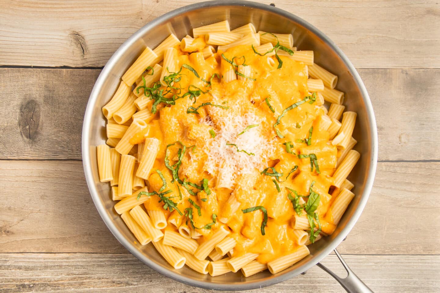 This is a picture of the cooked pasta with some sauce, parmesan and basil.