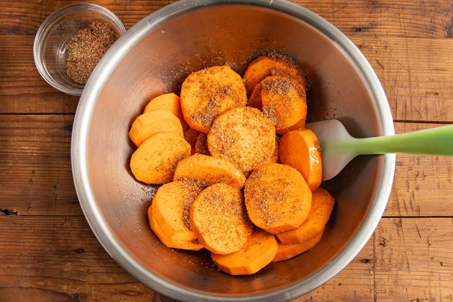This is a picture of the sweet potatoes in a bowl with oil with the seasoning added.