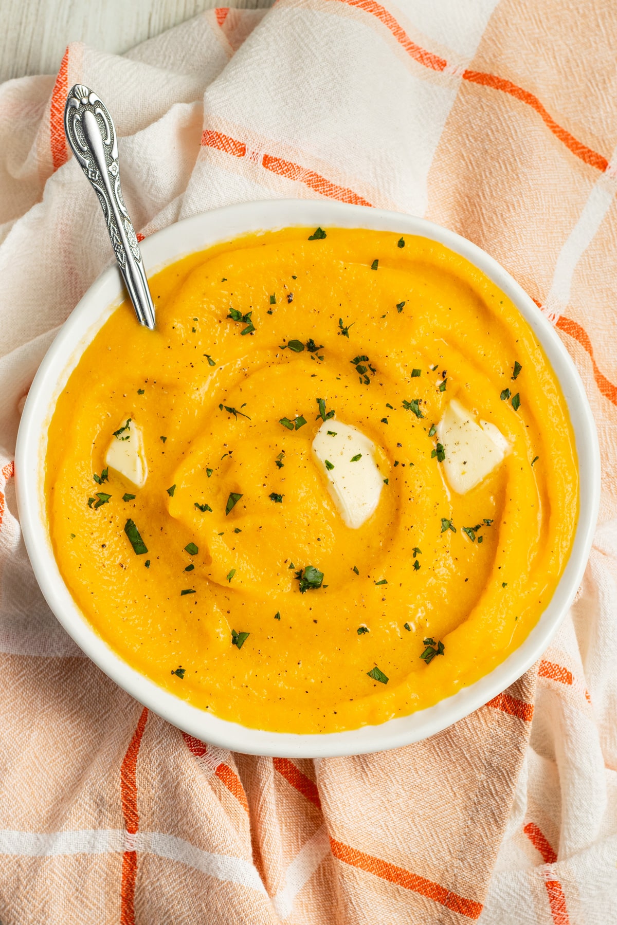 This is a bowl of mashed butternut squash with butter on top.