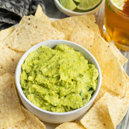 This is a picture of a bowl of guacamole with chips.