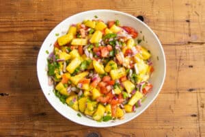 This is a picture of the ingredients chopped up in a bowl to make this pineapple pico de gallo.