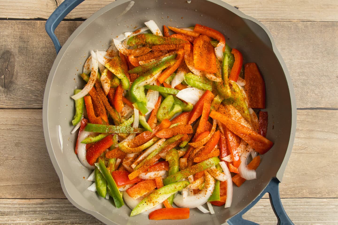 This is a picture of the chicken being cooked in a skillet with peppers and onions added.