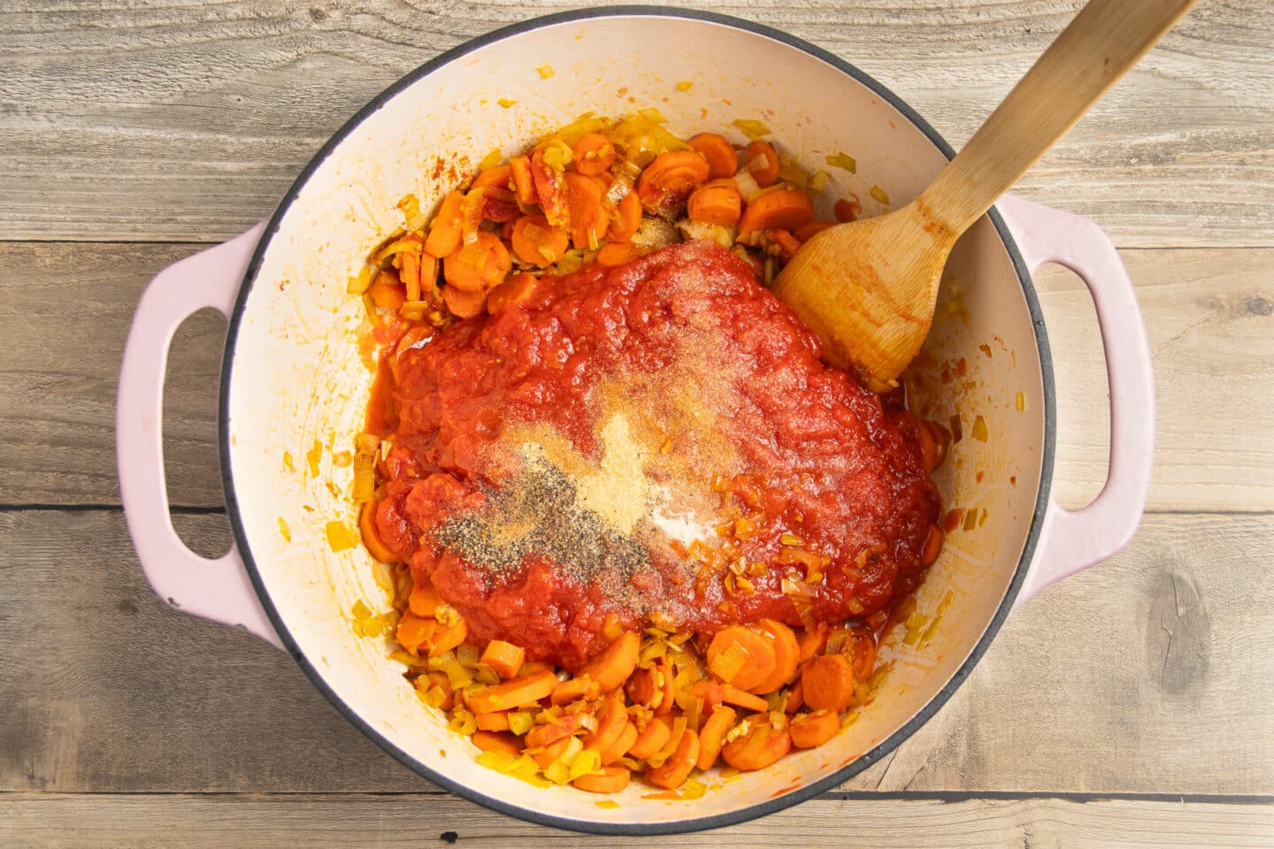 This is a picture of a pot with the veggies and crushed tomatoes added and seasoning added.