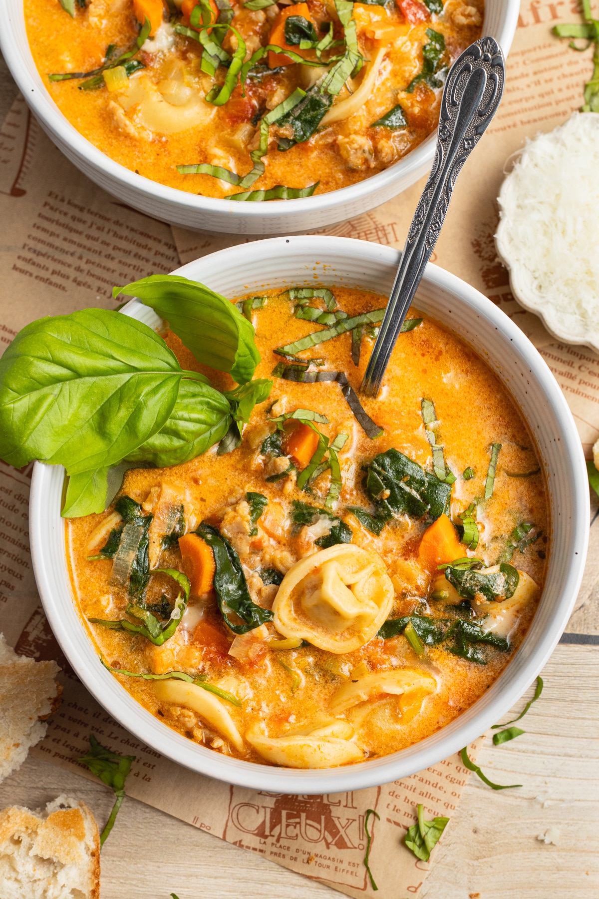 This is a picture of a bowl or tortellini soup with spinach and sausage.
