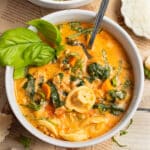 This is a picture of a bowl of tortellini soup with spinach and sausage.
