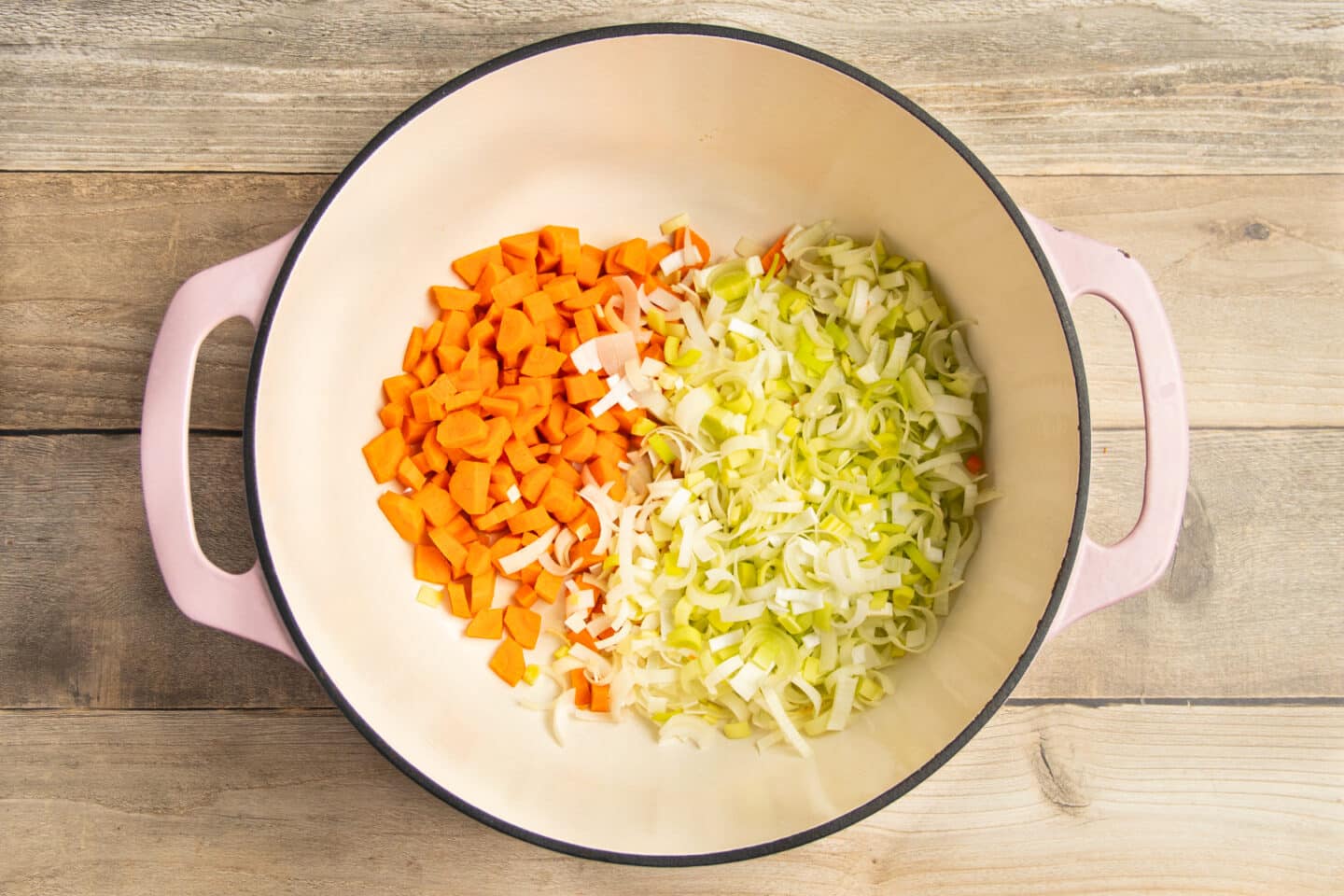 This is a picture of carrots and leeks being sautéed in a Dutch oven.