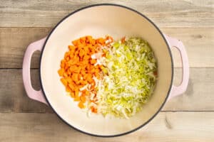 This is a picture of carrots and leeks being sautéed in a Dutch oven.